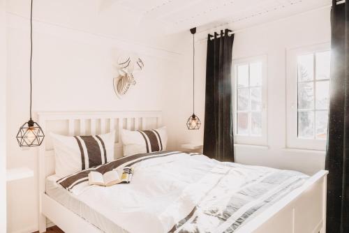 a white bedroom with a bed with a book on it at Harz Cottage Emma in Bad Lauterberg