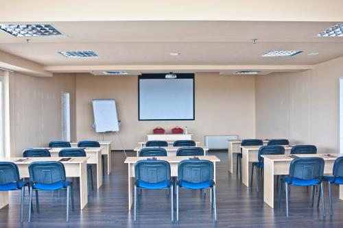 a classroom with tables and blue chairs and a screen at Canada Hotel Budapest in Budapest