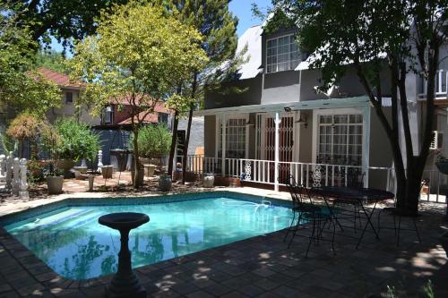 a swimming pool with chairs in front of a house at Hobbit Boutique Hotel in Bloemfontein