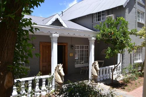 a house with two statues of horses in front of it at Hobbit Boutique Hotel in Bloemfontein