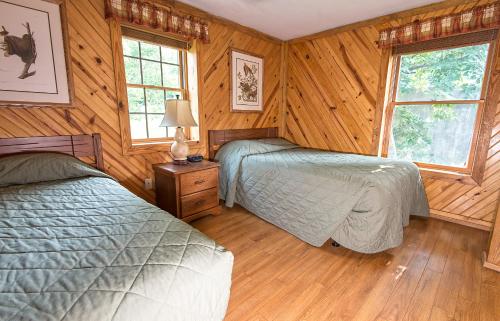 two beds in a bedroom with wooden walls and windows at General Butler State Resort Park in Carrollton