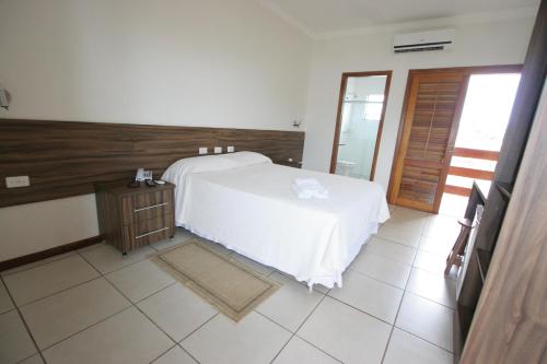 a bedroom with a white bed and a wooden wall at Ville Park Hotel in Ourinhos