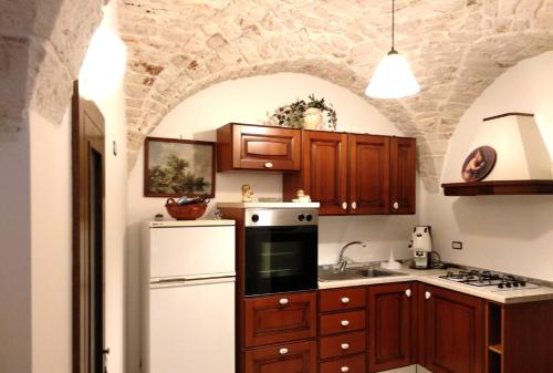 a kitchen with wooden cabinets and a white refrigerator at Dimora Santa Maria in Putignano