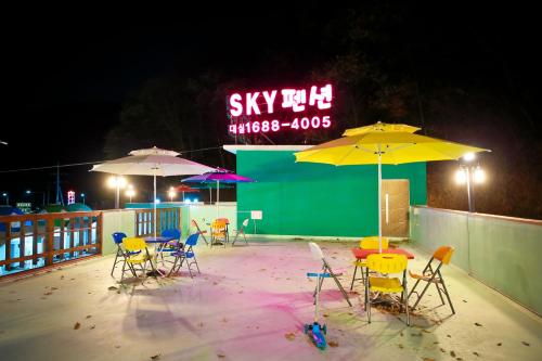 a group of chairs and umbrellas on a patio at night at Sky Vivaldi Pension in Hongcheon