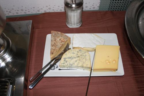 a plate with different types of cheese on a table at Logis Hôtel Restaurant de la Dore in Vertolaye