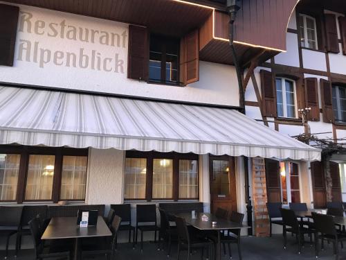 a restaurant with tables and chairs in front of a building at Alpenblick Ferenberg Bern in Stettlen