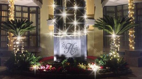 a building with christmas lights and palm trees and a sign at Hotel Chic in SantʼAntimo