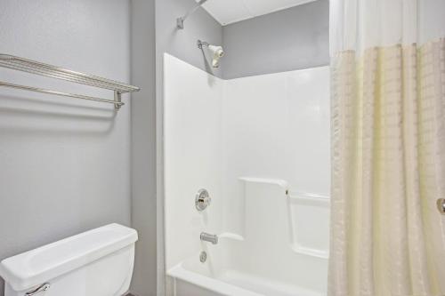 a bathroom with a white toilet and a shower at Days Inn by Wyndham Great Lakes - N. Chicago in North Chicago