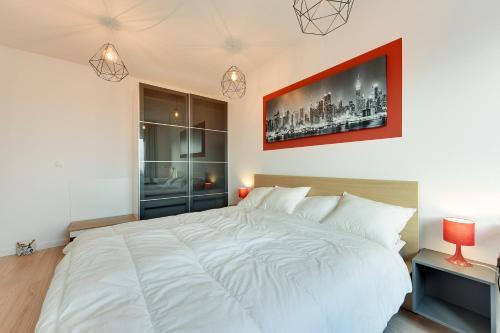 a bedroom with a large white bed with a picture on the wall at Aviator Modern 50 in Gdańsk