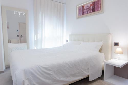 a white bedroom with a white bed and a lamp at Corte Maggiore in Ravenna