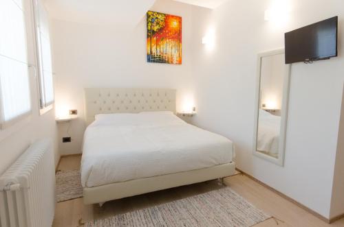 a white bedroom with a bed and a tv on the wall at Corte Maggiore in Ravenna