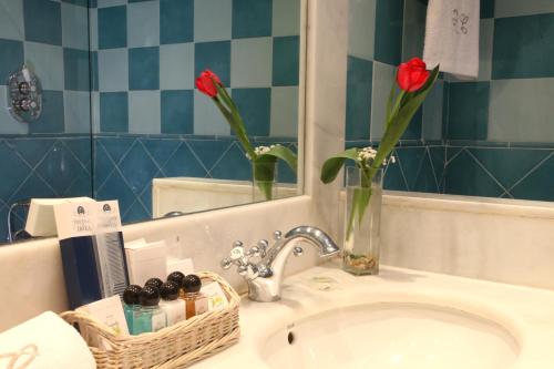 un lavabo con dos flores rojas en un jarrón en La Quinta de los Cedros, en Madrid