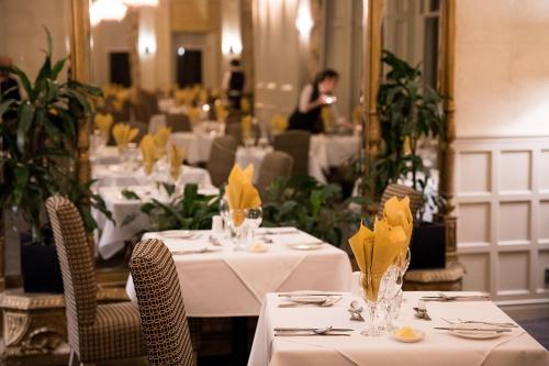 a restaurant with white tables and chairs and a woman in the background at Keswick Country House Hotel in Keswick