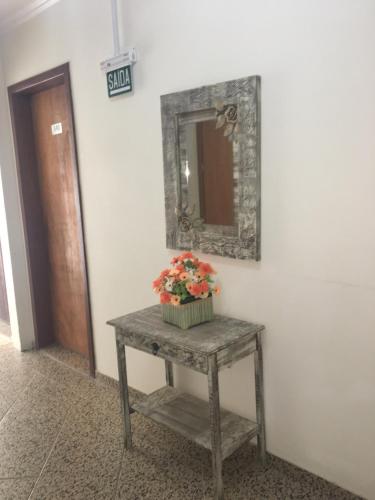 a table with a mirror and a potted plant on it at Hotel Mares do Sul in Tramandaí