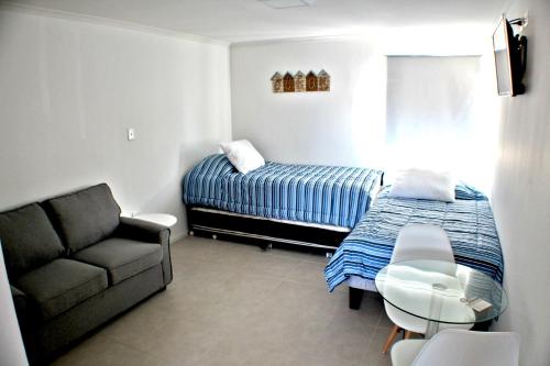 a bedroom with a bed and a couch and a chair at Playa Hotel - Cavancha in Iquique