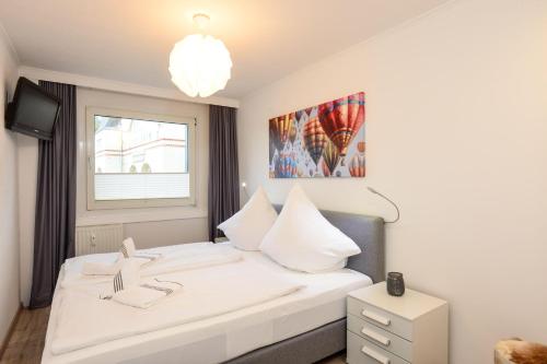 een slaapkamer met een wit bed en een raam bij Sylter-Rose-Haus-Ankerlicht-Wohnung-72 in Westerland