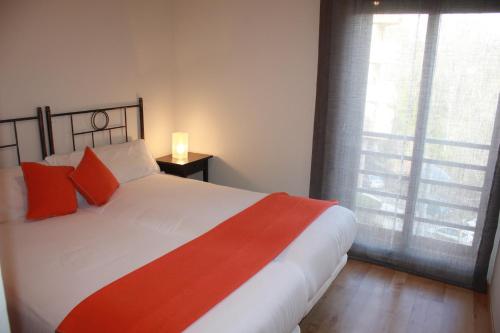 Schlafzimmer mit einem Bett mit roten Kissen und einem Fenster in der Unterkunft Apartamento Ainsa Pirineo in Aínsa