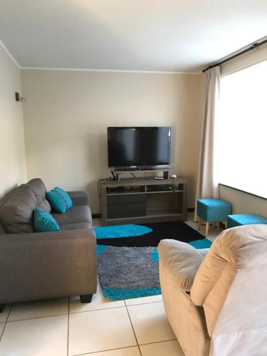 uma sala de estar com um sofá e uma televisão de ecrã plano em Casa Los Robles em Pucón
