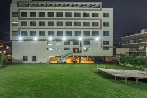 a large white building with a green lawn in front of it at Hotel Abika Elite in Ujjain