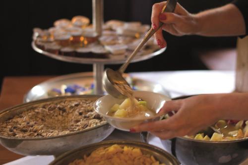 a person holding a bowl of food on a buffet at Hotel Mariandl in Munich
