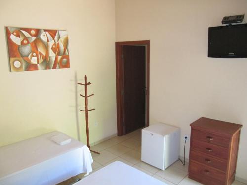 Cette chambre comprend un lit, une commode et une télévision. dans l'établissement Eco Pousada Villa Verde, à Bonito