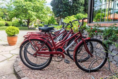 uma fila de bicicletas vermelhas estacionadas ao lado de um edifício em Vila Suzana Parque Hotel em Canela