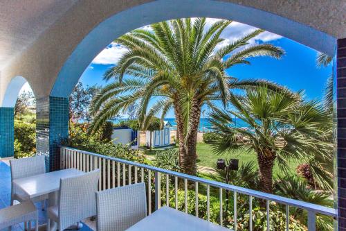 a balcony with a table and chairs and palm trees at Hotel Poseidon in Diamante