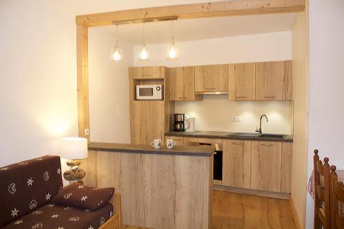 a kitchen with wooden cabinets and a couch in a living room at Maison Salina in Samoëns