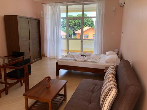 a living room with a couch and a large window at Green Turaco in Zanzibar City