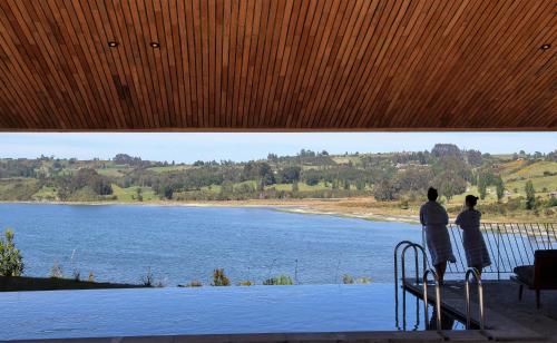 two people standing on a railing looking at a lake at Refugia Chiloé in San José
