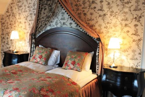 a bedroom with a bed and two night stands with lamps at Hotel Wassilioff - Unike Hoteller in Stavern