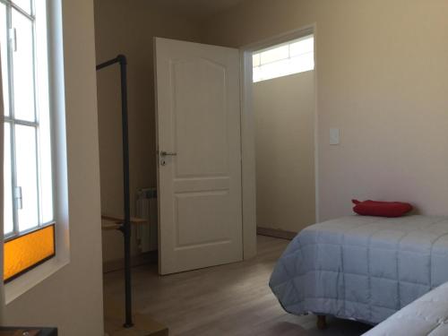 1 dormitorio con 1 cama y puerta con ventana en Wind Puerto Madryn en Puerto Madryn