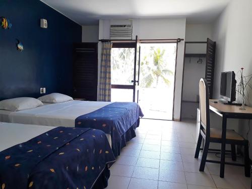 a bedroom with two beds and a desk with a computer at Hotel D'Anatureza in Maceió