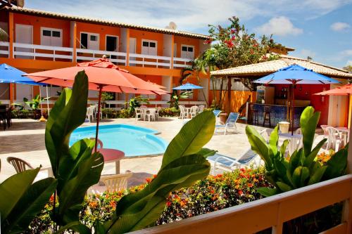 a resort with a pool and tables and umbrellas at Capitães de Areia Pousada in Praia do Frances