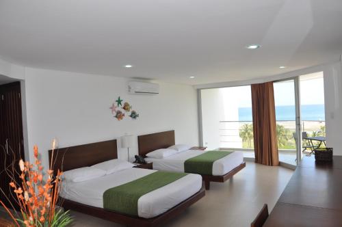 two beds in a room with a view of the ocean at Hotel Isla Verde in Tubará
