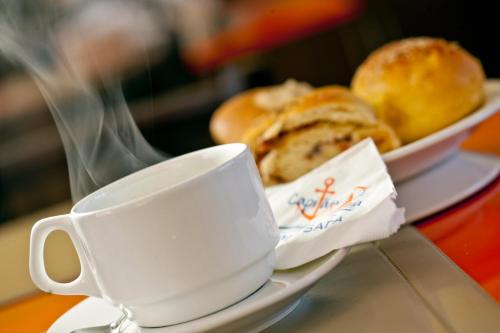 a plate of bread and a cup on a table at Capitães de Areia Pousada in Praia do Frances