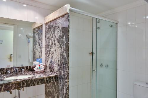 a bathroom with a glass shower and a sink at Dubai Macaé by Atlântica in Macaé