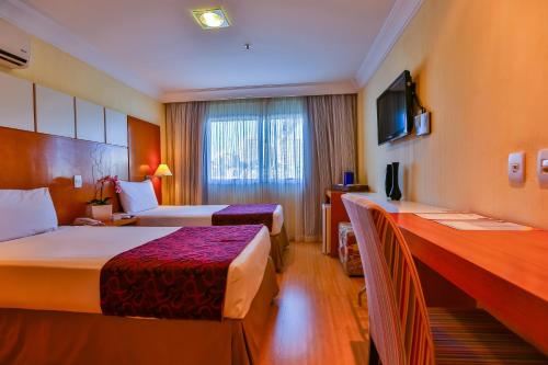 a hotel room with two beds and a window at Dubai Macaé by Atlântica in Macaé
