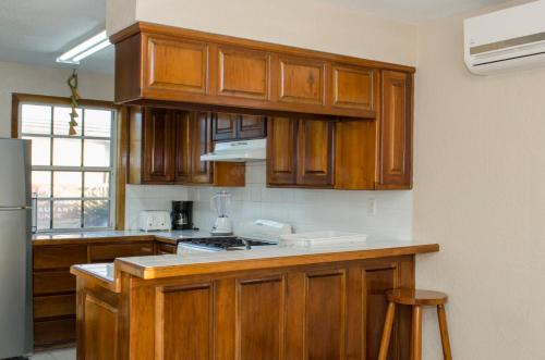 Una cocina con gabinetes de madera y encimera. en Casa Brisa Guest House, en San Pedro