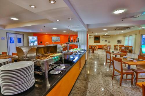 a restaurant with a buffet line with tables and chairs at Dubai Macaé by Atlântica in Macaé
