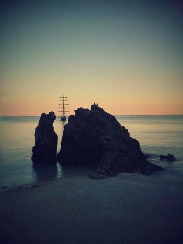 a rock in the ocean with a ship in the water at da Benedetta in Monterosso al Mare
