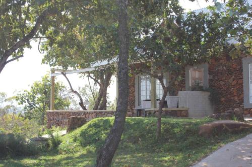 a house with a stone wall and trees at Ashbourne Country Escape Hazyview in Hazyview