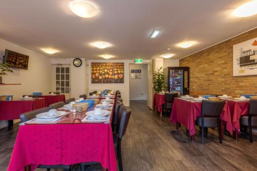 a dining room with tables and chairs with pink table cloth at Hotel Randenbroek in Amersfoort