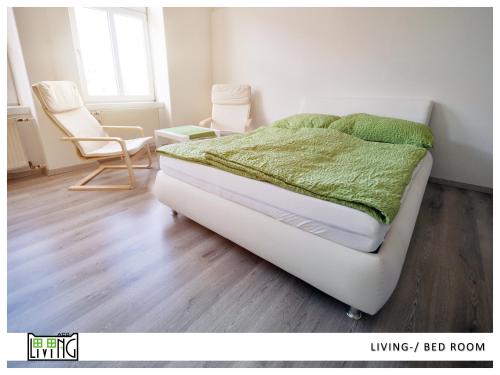 a bedroom with a bed and two chairs in it at ACO Living - A Cheap Overnight in Klagenfurt