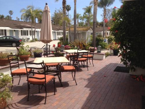 a patio with tables and chairs and an umbrella at Marina Beach Motel in Santa Barbara