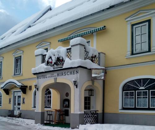 a yellow building with snow on top of it at Hotel zum goldenen Hirschen in Göstling an der Ybbs