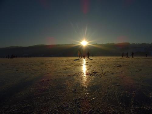 a group of people walking on the beach at sunset at Sunnhof in Oberhofen am Irrsee
