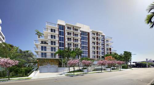 a large apartment building on a street with flowering trees at Grand Beach Hotel Bay Harbor in Miami Beach