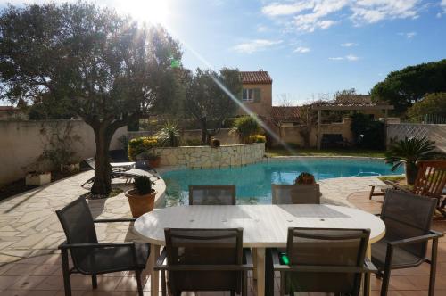 un patio avec une table et des chaises et une piscine dans l'établissement Mer et Soleil, à Sausset-les-Pins