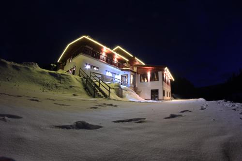 a building with lights on it in the snow at night at Hotel Studničky in Vernár